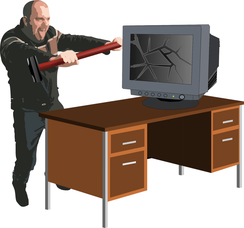 Angry man with hammer and smashed computer 