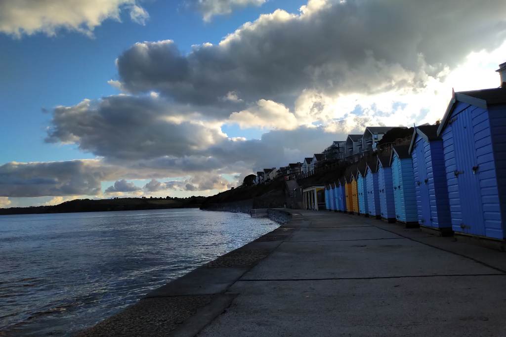 Row of beach huts at Castle Beach at high tide