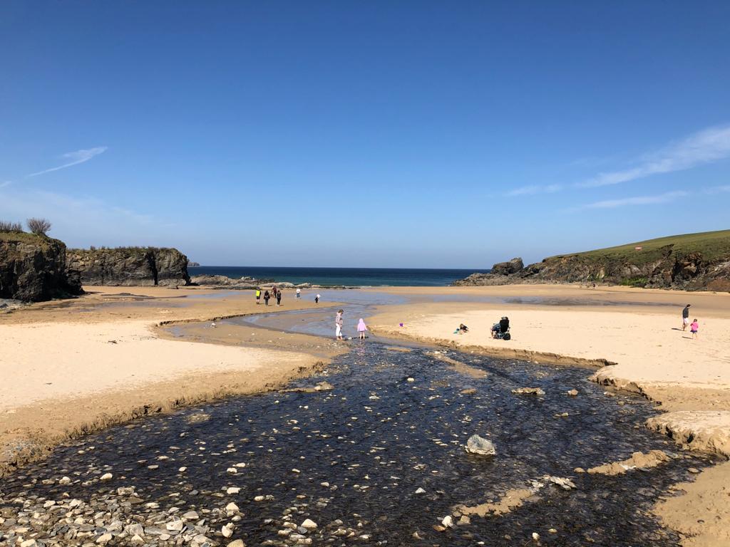 Trevone beach with a person using a sand wheelchair and other people dotted around