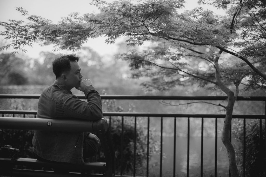 man contemplating by a tree in black and white
