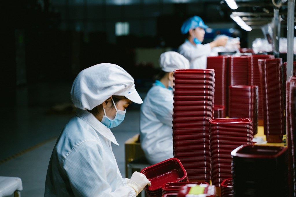 Women in masks working in an assembly line